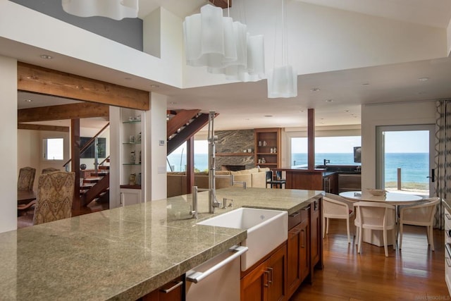 kitchen featuring dishwasher, a high ceiling, dark wood-type flooring, a water view, and a fireplace