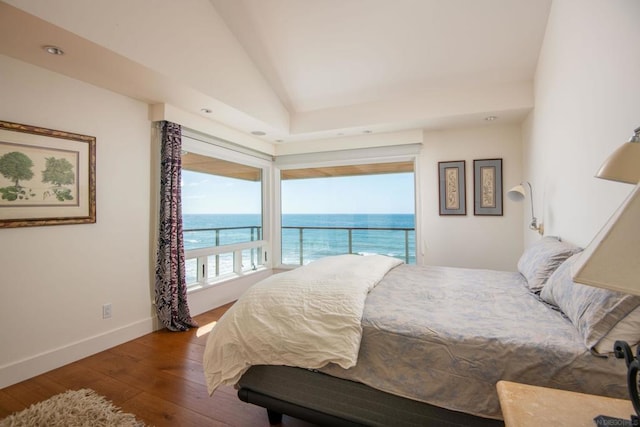 bedroom with a water view, lofted ceiling, and hardwood / wood-style floors