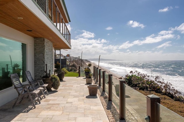 exterior space with a view of the beach, a water view, and a balcony