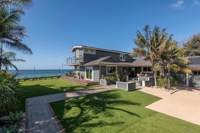 rear view of house featuring a patio area, a lawn, a water view, and a balcony