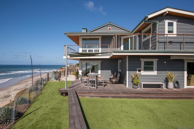 rear view of property with a yard, a view of the beach, a water view, and a balcony