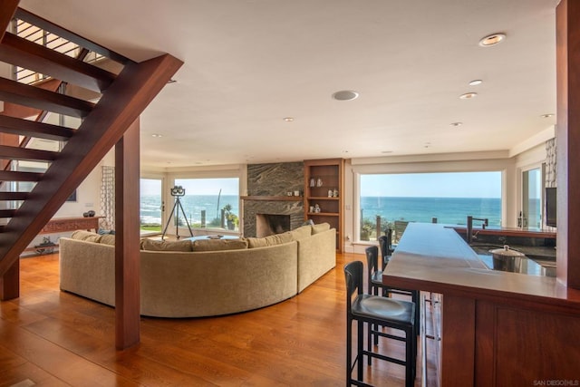 living room with a water view, a fireplace, and hardwood / wood-style floors