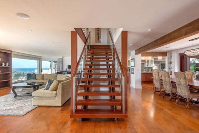 staircase with beam ceiling and hardwood / wood-style flooring