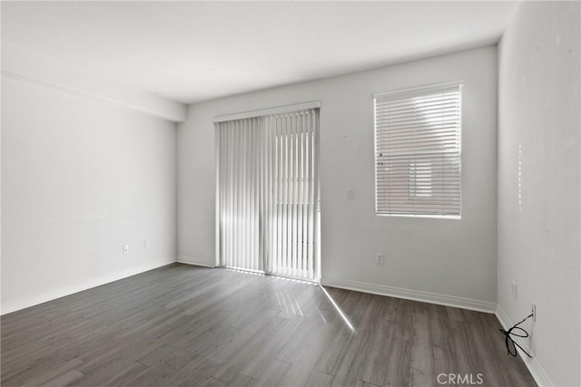 unfurnished room featuring a wealth of natural light and dark wood-type flooring