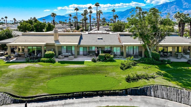 back of property featuring a mountain view, a lawn, and a patio