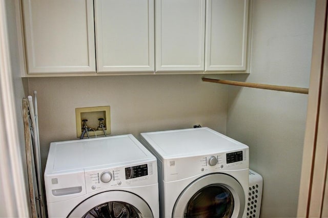 clothes washing area with separate washer and dryer and cabinets