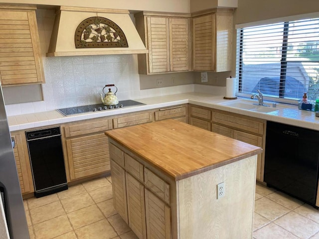 kitchen with light brown cabinets, light tile patterned floors, black appliances, and a kitchen island