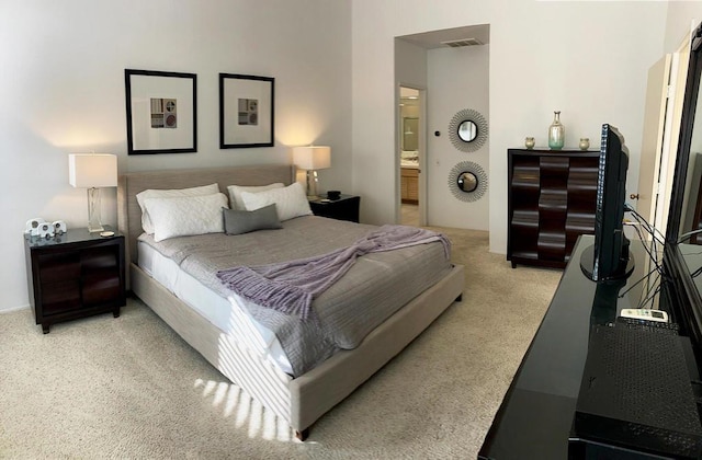 bedroom featuring light carpet and ensuite bath