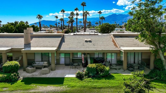 back of property featuring a mountain view, a patio area, and a yard