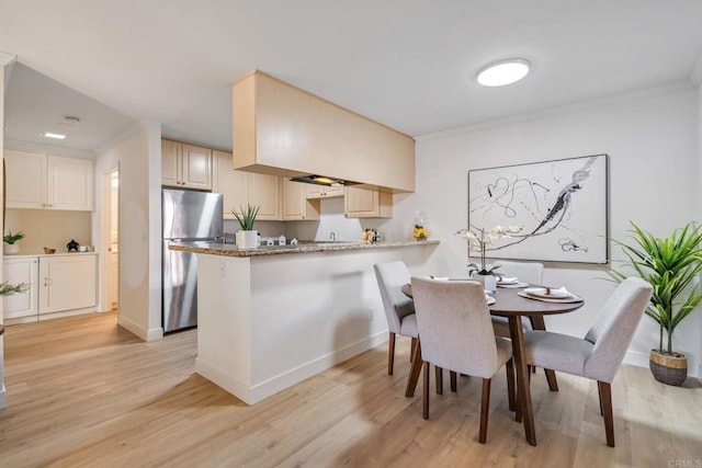 dining room with crown molding and light hardwood / wood-style floors