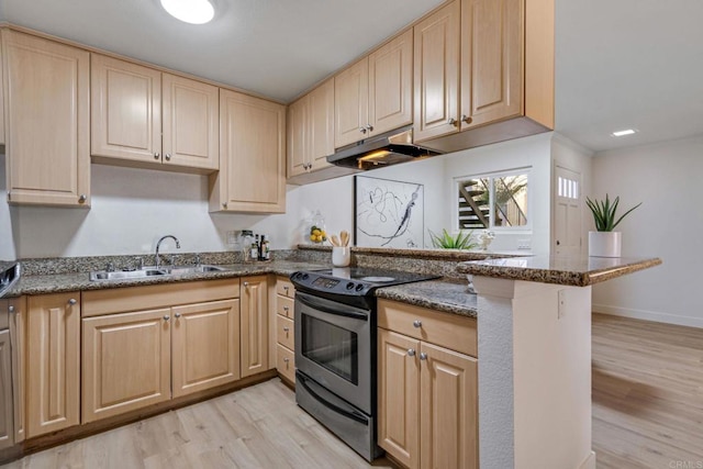 kitchen with black / electric stove, sink, dark stone counters, and light hardwood / wood-style flooring