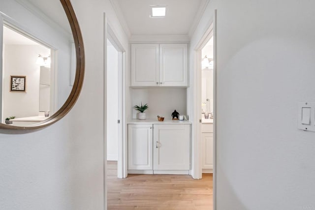 hall with light wood-type flooring and ornamental molding