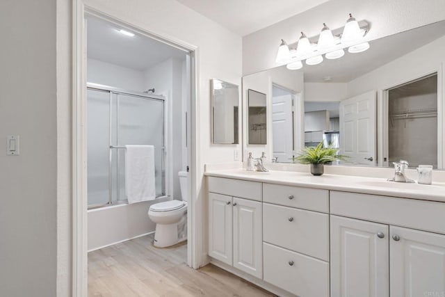 full bathroom featuring hardwood / wood-style floors, vanity, toilet, and enclosed tub / shower combo