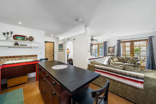 kitchen with light carpet, a center island, ceiling fan, and french doors