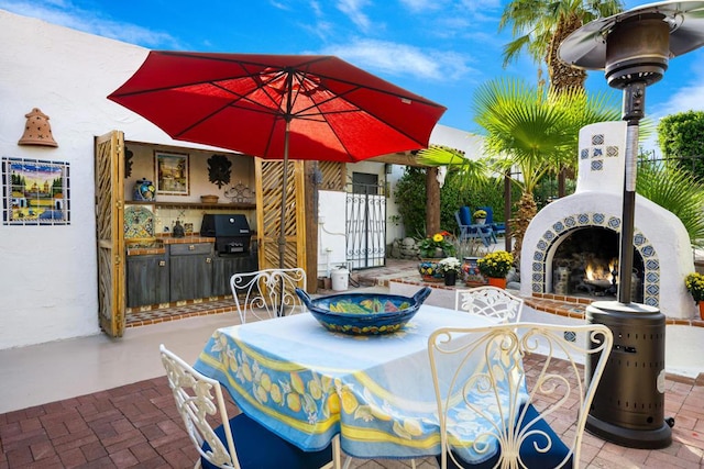 view of patio / terrace with an outdoor brick fireplace and a grill