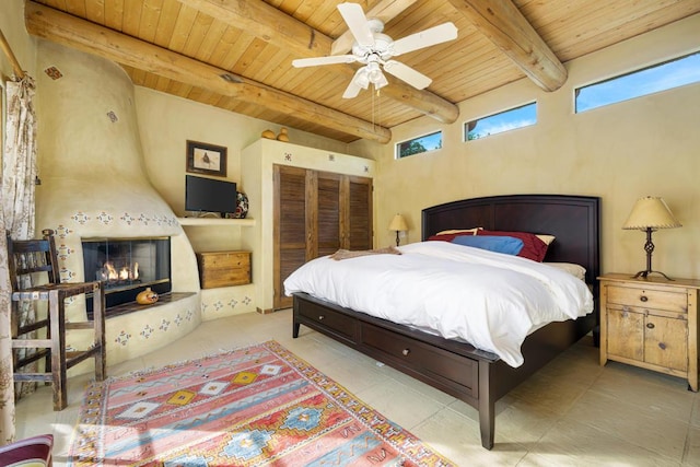 bedroom featuring beam ceiling, light tile patterned floors, ceiling fan, and wood ceiling