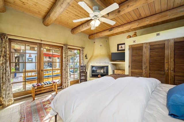 bedroom with beam ceiling, ceiling fan, a fireplace, and wooden ceiling