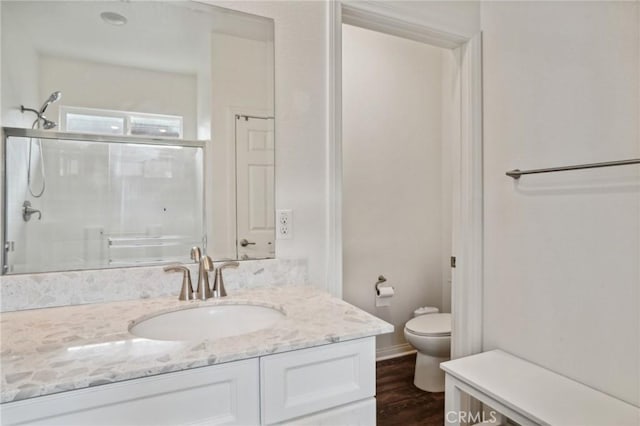 bathroom with vanity, wood-type flooring, an enclosed shower, and toilet