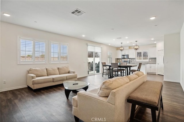 living room with a chandelier, dark hardwood / wood-style flooring, and a wealth of natural light