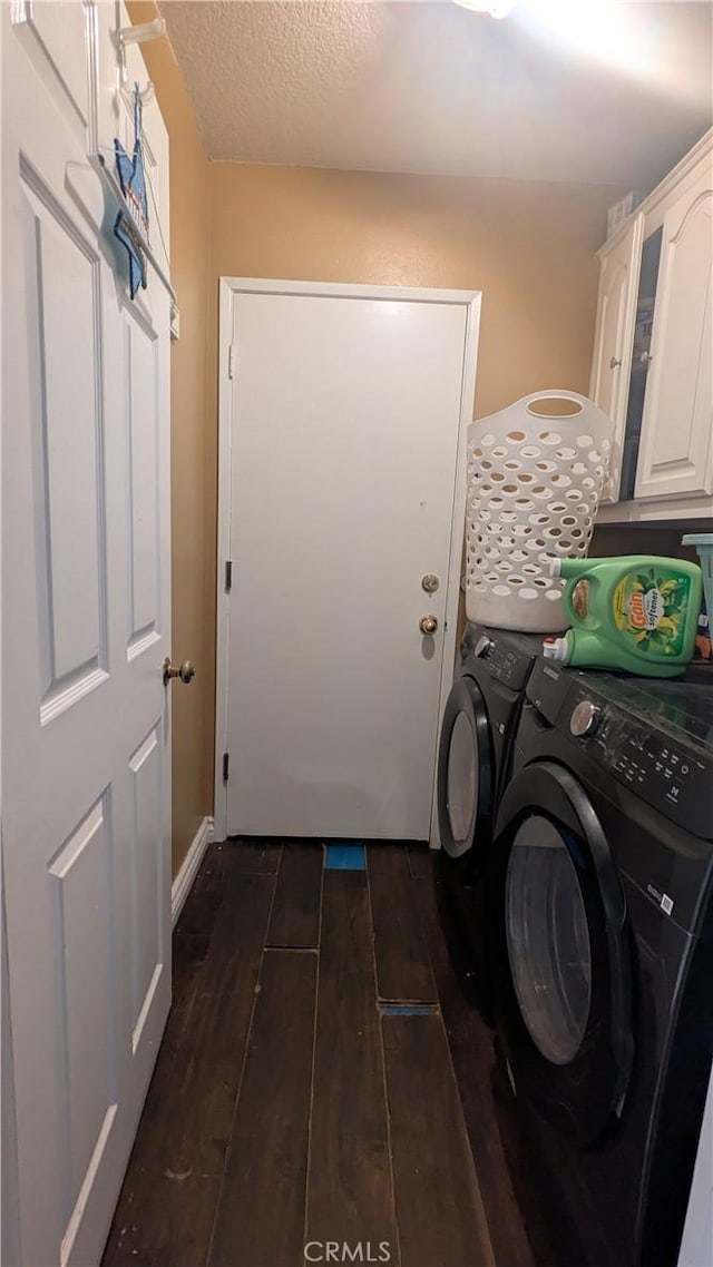 clothes washing area featuring washer and dryer, dark hardwood / wood-style flooring, cabinets, and a textured ceiling