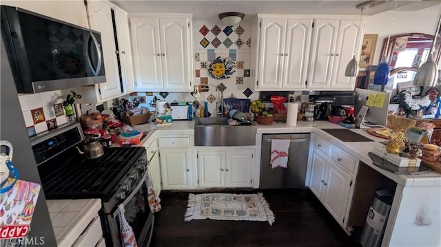 kitchen featuring white cabinetry, sink, backsplash, tile countertops, and appliances with stainless steel finishes