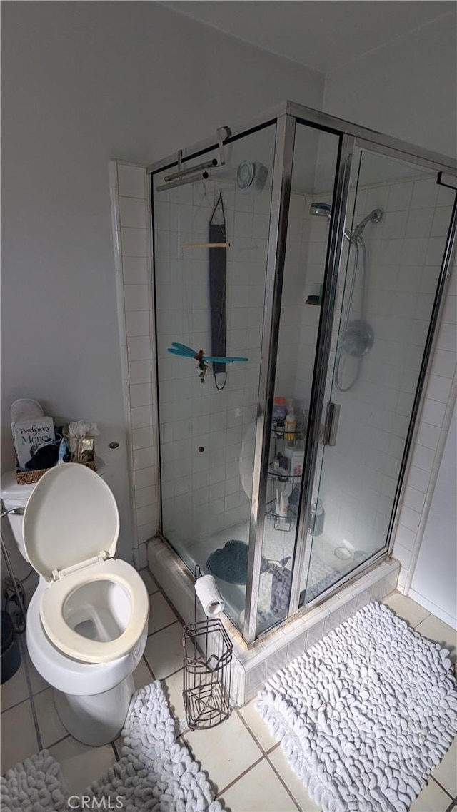 bathroom featuring tile patterned floors, an enclosed shower, and toilet