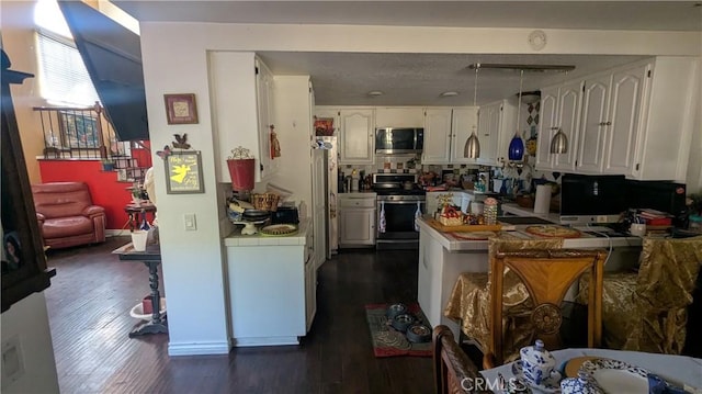 kitchen with kitchen peninsula, stainless steel appliances, dark wood-type flooring, white cabinetry, and tile counters