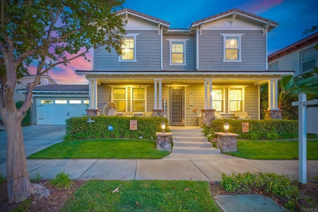 view of front of home with a porch, a garage, and a lawn