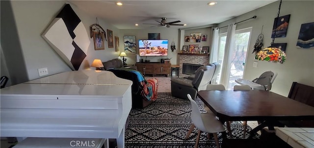 living room featuring a stone fireplace and ceiling fan