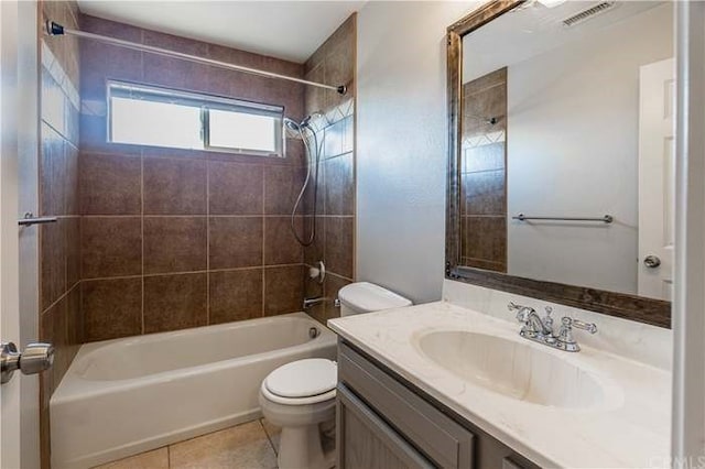 full bathroom with tile patterned flooring, vanity, tiled shower / bath combo, and toilet