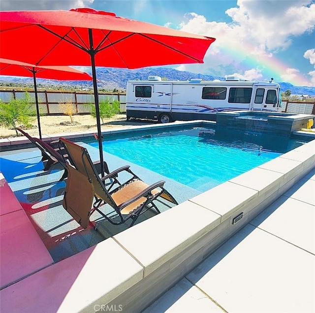 view of swimming pool featuring a mountain view and an in ground hot tub