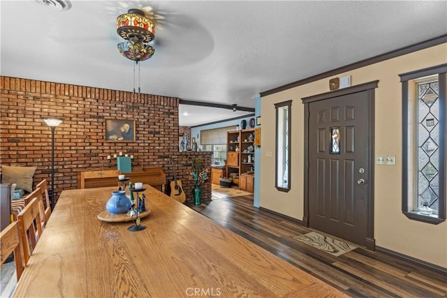 interior space with dark hardwood / wood-style floors, ornamental molding, and brick wall