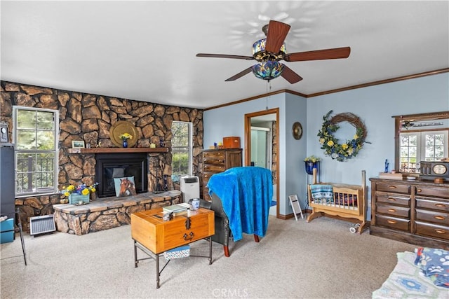 carpeted living room featuring a stone fireplace, ceiling fan, a healthy amount of sunlight, and ornamental molding