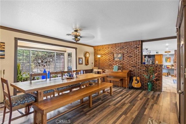 24601 Deertrail Dr, Tehachapi, CA 93561 - dining area with wood finished floors, a textured ceiling, ornamental molding, brick wall, and a ceiling fan