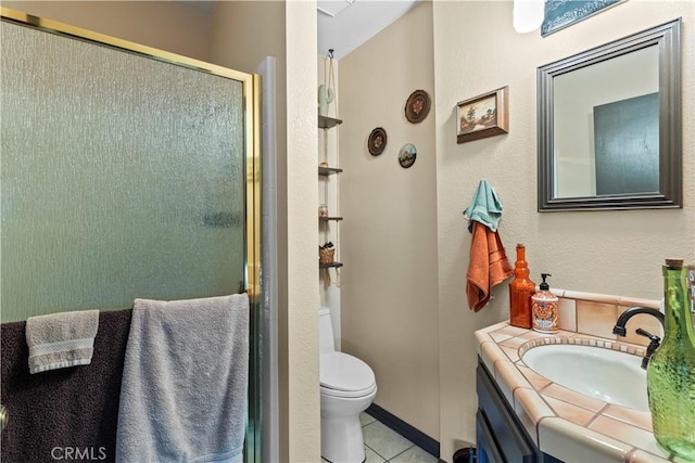 bathroom featuring tile patterned flooring, vanity, toilet, and walk in shower