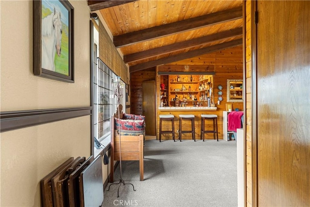 interior space featuring vaulted ceiling with beams, bar area, carpet floors, wooden walls, and wood ceiling