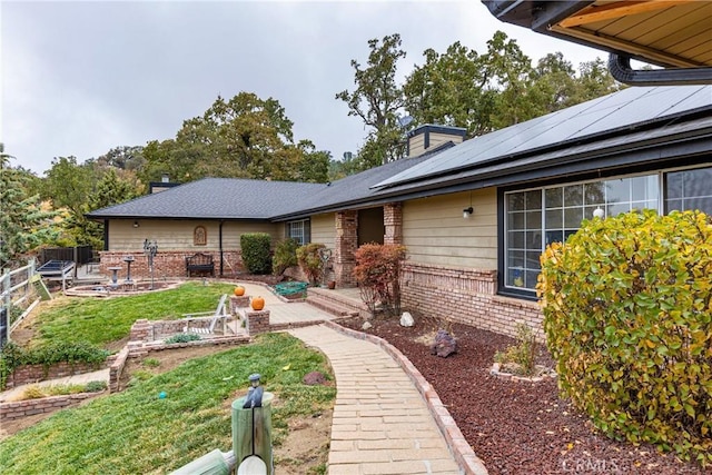 rear view of house featuring a lawn, a patio, and solar panels