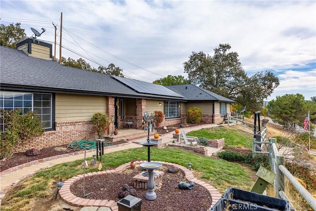 back of house featuring a yard and solar panels