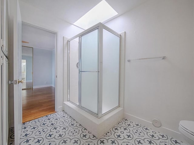 bathroom with a skylight, toilet, tile patterned flooring, and a shower with door