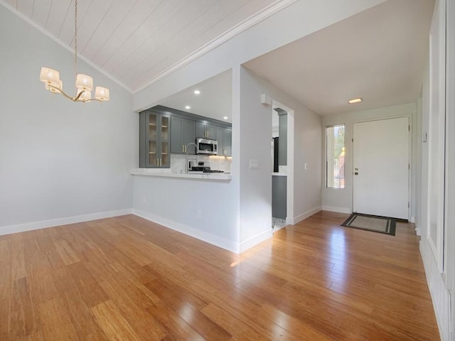 entrance foyer with lofted ceiling, hardwood / wood-style flooring, ornamental molding, and a chandelier