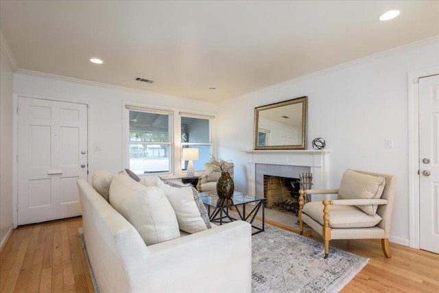 living room with crown molding, a fireplace, and light hardwood / wood-style flooring