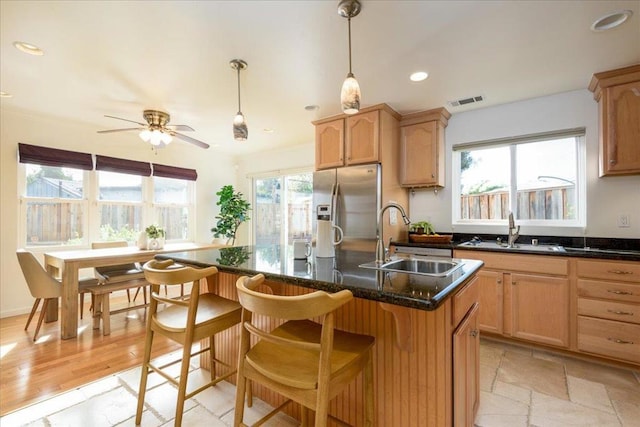 kitchen featuring stainless steel fridge with ice dispenser, ceiling fan, sink, and an island with sink