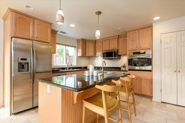 kitchen with dark stone countertops, pendant lighting, a center island, sink, and appliances with stainless steel finishes