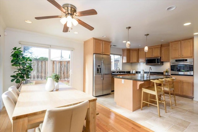 kitchen with hanging light fixtures, ornamental molding, stainless steel appliances, and a center island