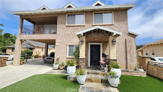 view of front facade featuring a balcony and a front yard