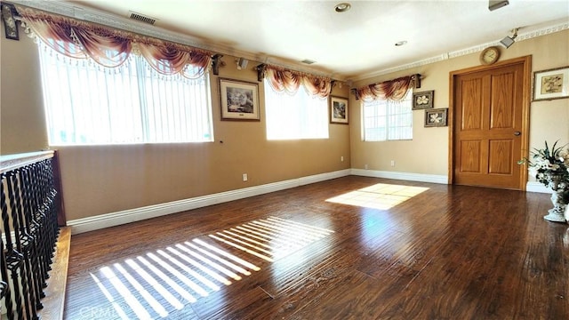 spare room featuring dark wood-type flooring and crown molding