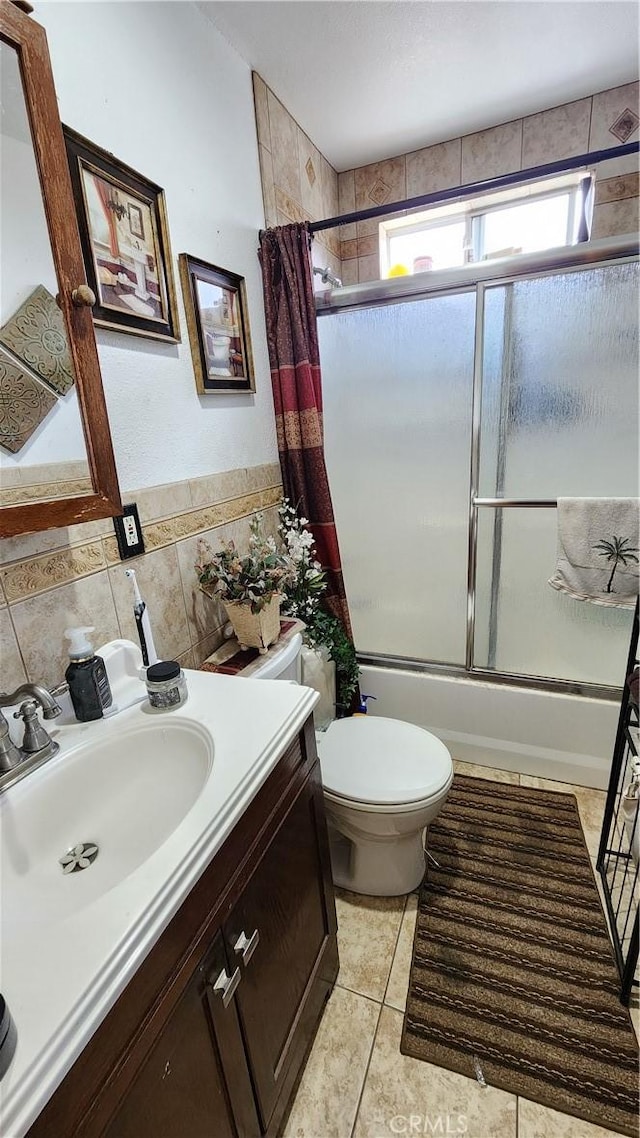 full bathroom featuring toilet, shower / tub combo with curtain, tile patterned flooring, tile walls, and vanity