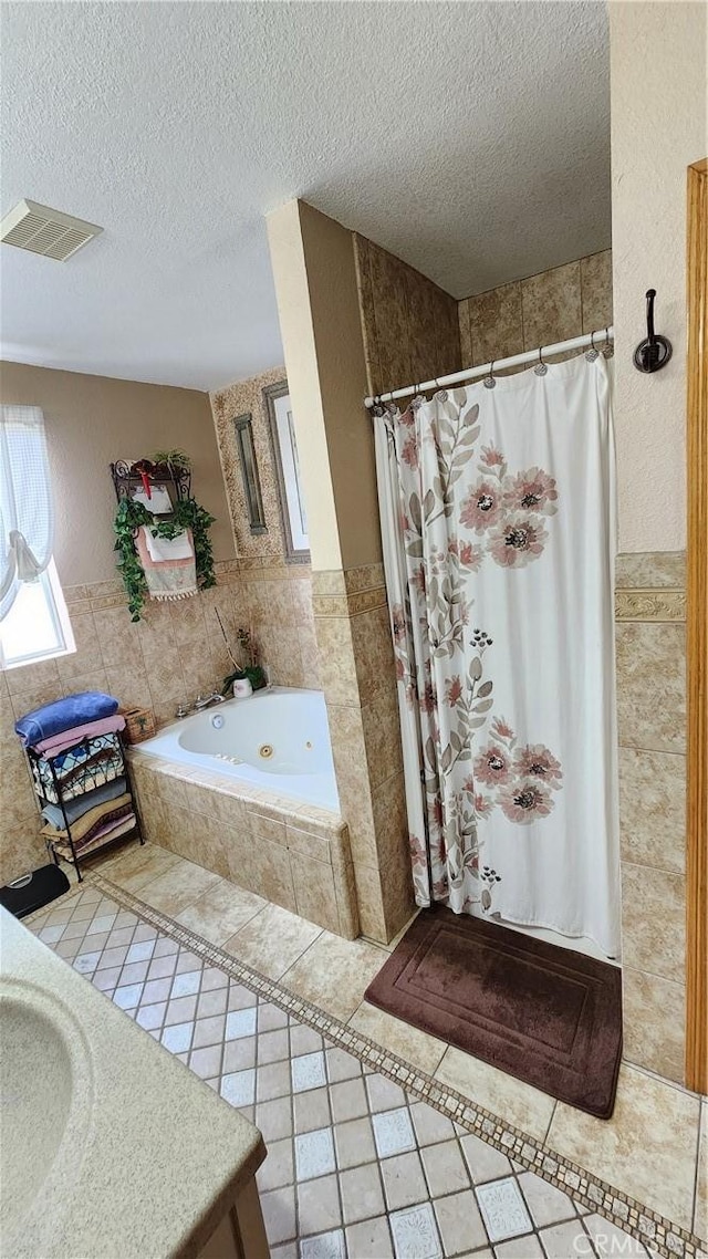 bathroom featuring tile patterned flooring, a textured ceiling, vanity, and plus walk in shower