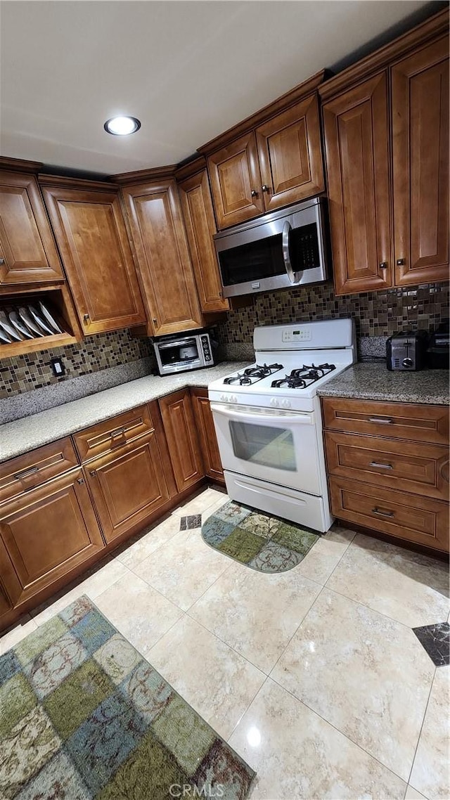 kitchen with backsplash, white range with gas stovetop, and light tile patterned flooring