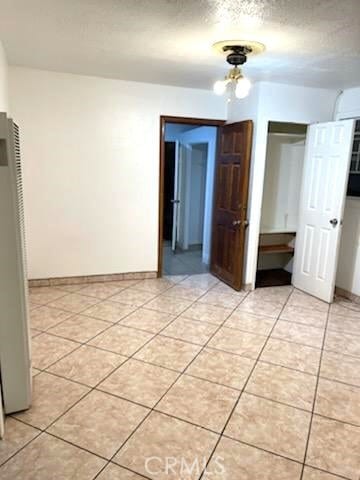 interior space with a textured ceiling, a closet, and stainless steel fridge